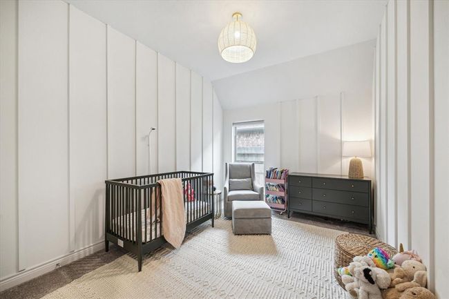 This charming secondary bedroom features paneled walls and a designer light fixture, making it a versatile space perfect for everyone, from a nursery to overnight guests. | Image 22
