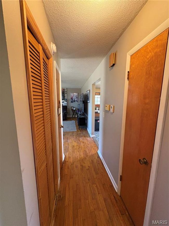 Corridor featuring hardwood / wood-style flooring, baseboards, and a textured ceiling | Image 19