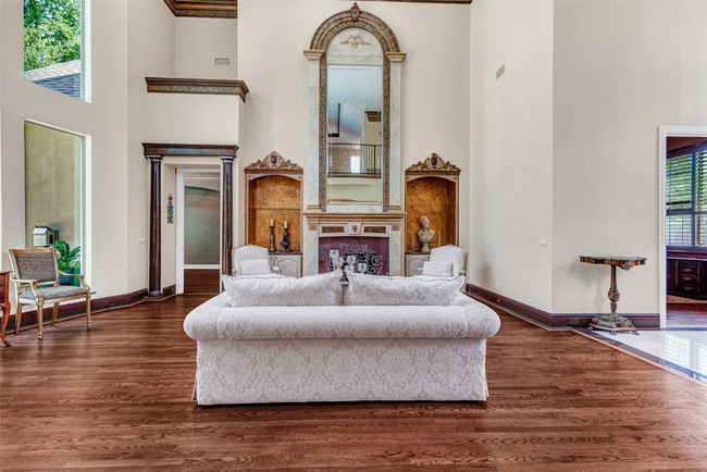 The fireplace is reminiscent of a French chateaux with the tall mirrored mantle and beautifully detailed art niches with built-in cabinets on either side. The ornate crown molding is everywhere, as is the recently refinished wood floors! | Image 6