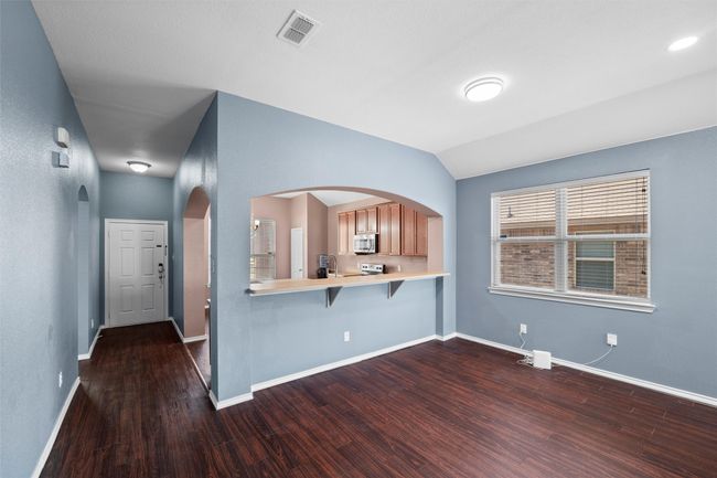 Kitchen featuring visible vents, light countertops, a breakfast bar, stainless steel appliances, and dark wood-type flooring | Image 13