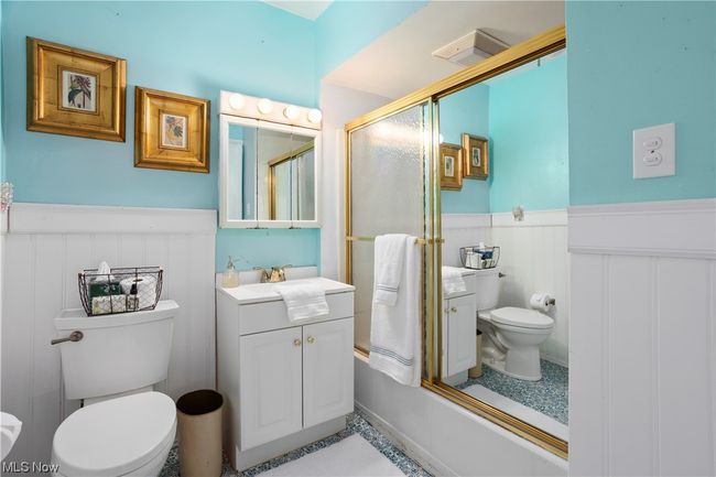 Full bathroom featuring bath / shower combo with glass door, oversized vanity, mirror, and light tile floors | Image 19