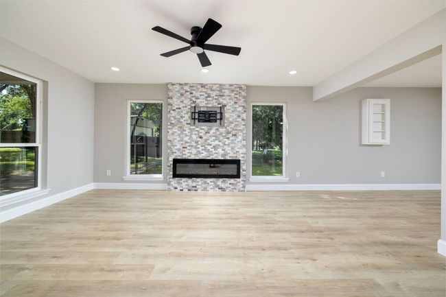 Unfurnished living room featuring a stone fireplace, wood finished floors, recessed lighting, and ceiling fan | Image 13