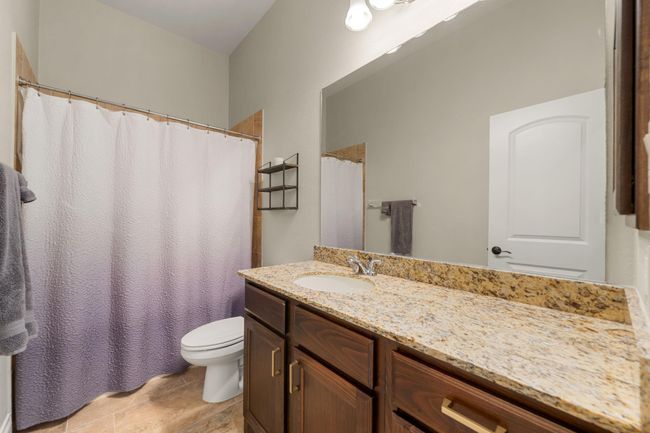 Secondary bathroom features granite countertops and dark cabinets, neutral paint, shower/tub combo with tile surround, large mirror, tile floors, sleek fixtures and plenty of space to accommodate any visiting family or guests. | Image 27