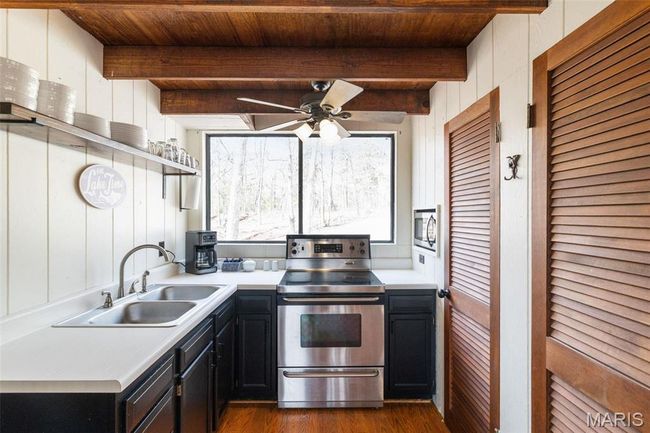 Kitchen with beam ceiling, open shelves, a sink, appliances with stainless steel finishes, and dark cabinets | Image 20