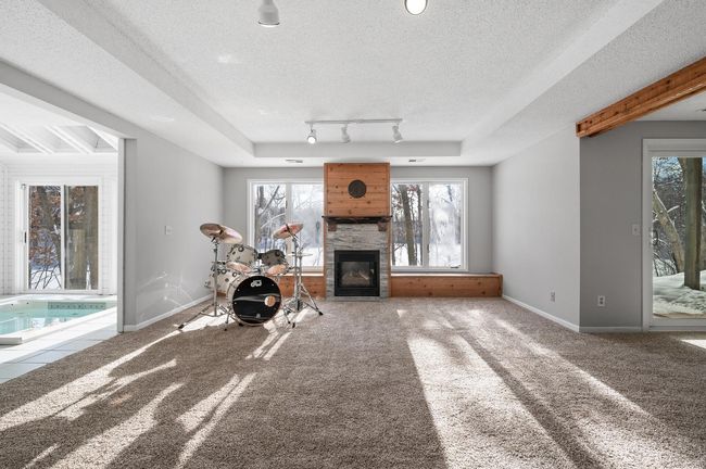 The generously sized lower level family room features a gas fireplace with a tile surround and built-in window seats with storage underneath on both sides. | Image 30
