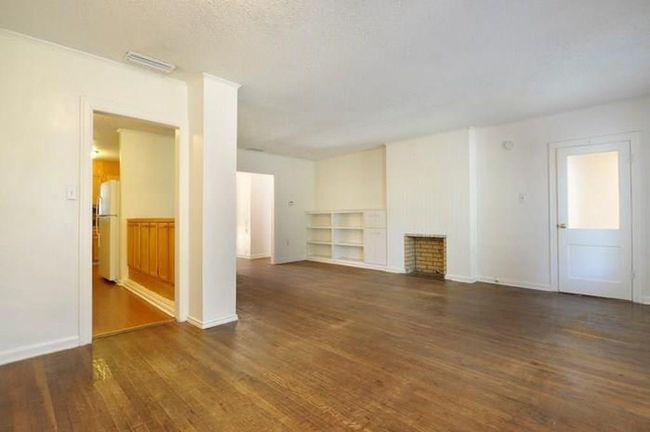 Unfurnished living room with wood finished floors and a fireplace | Image 4