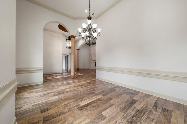 Unfurnished dining area featuring arched walkways, an inviting chandelier, wood finished floors, and recessed lighting | Image 6