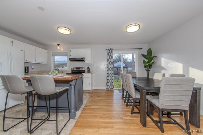 Kitchen featuring stainless steel range with electric stovetop, light hardwood / wood-style floors, white fridge, white cabinetry, and a breakfast bar area | Image 15