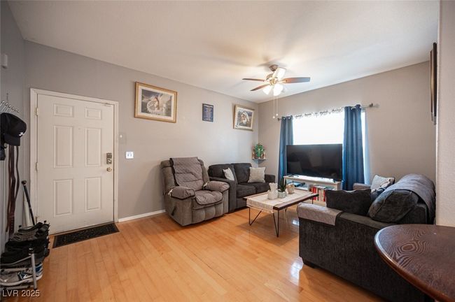 Living room with light wood-type flooring, ceiling fan, and baseboards | Image 5