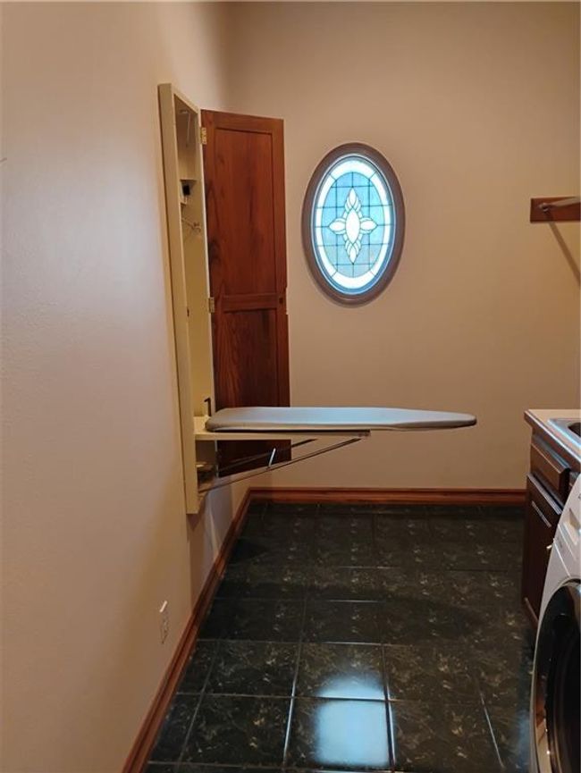 Washroom with oak baseboards, fold down ironing board laundry area, and washer / clothes dryer | Image 39