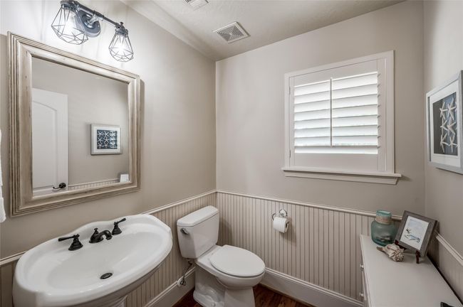 Located down the garage hallway, discover an inviting, spacious half bath featuring a stylish pedestal sink. | Image 24
