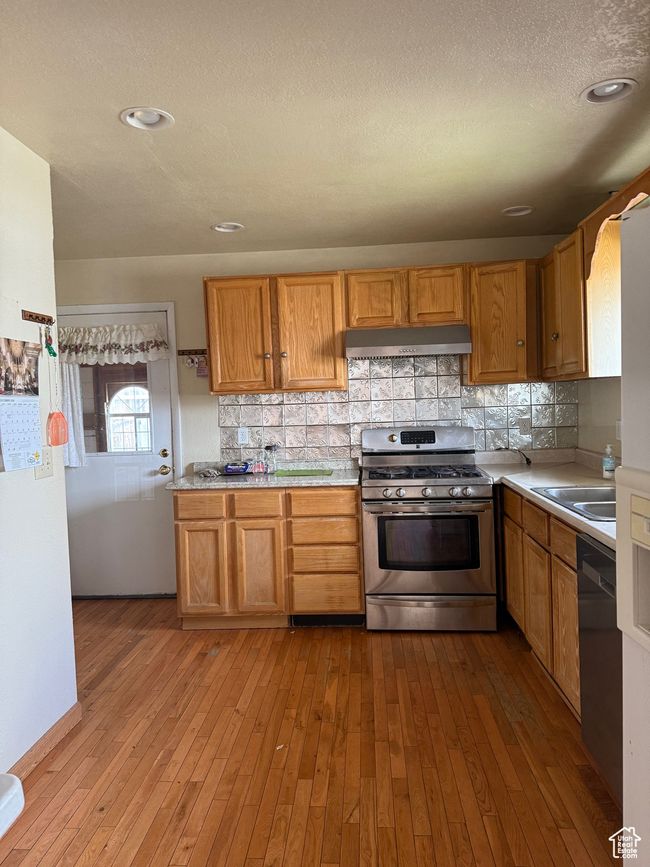 Kitchen featuring dishwasher, under cabinet range hood, stainless steel gas range oven, and light countertops | Image 7