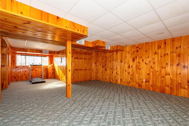 Basement with carpet flooring, a drop ceiling, and wood walls | Image 29