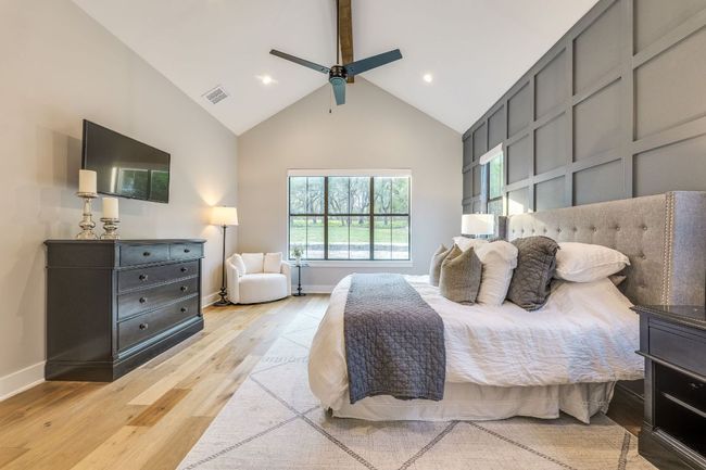 The impressive primary suite features vaulted ceilings, an exposed cedar beam, display windows overlooking the lush yard and an equally impressive ensuite. | Image 21