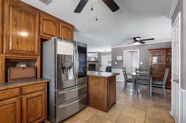 Kitchen with crown molding, ceiling fan, stainless steel fridge, and light tile flooring | Image 19