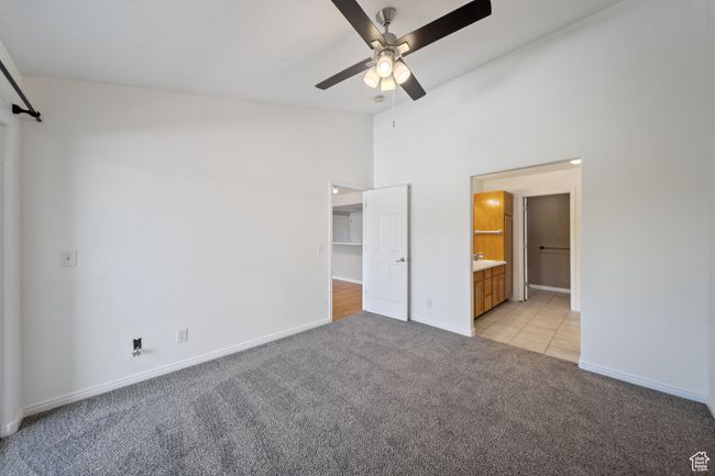 Unfurnished bedroom featuring light carpet, high vaulted ceiling, ensuite bathroom, a walk in closet, and light tile patterned floors | Image 17