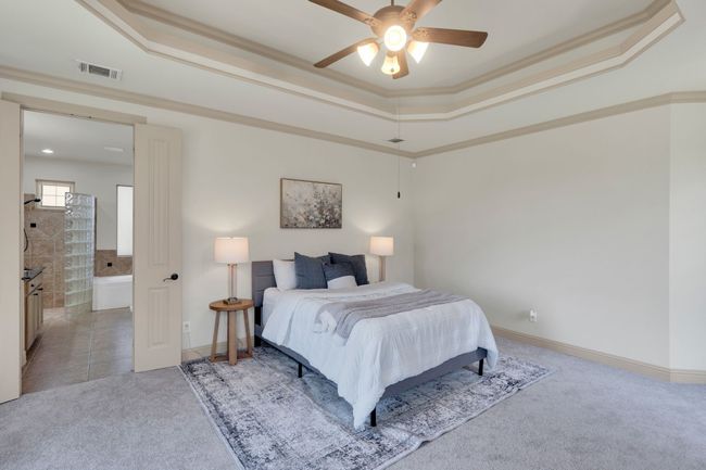 Bedroom featuring light carpet, a raised ceiling, ornamental molding, ceiling fan, and ensuite bath | Image 15