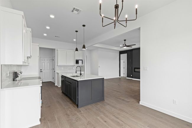 Kitchen with visible vents, built in microwave, white cabinets, tasteful backsplash, and a sink | Image 20