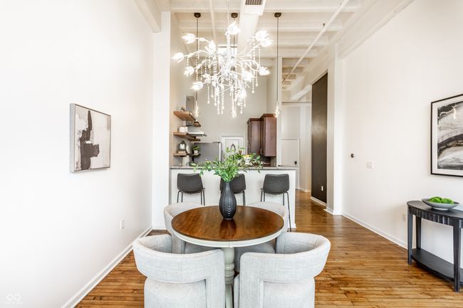 dining space featuring a chandelier, hardwood / wood-style flooring, beam ceiling, and a high ceiling | Image 12