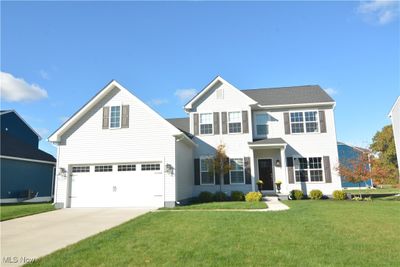 View of front of property featuring a front yard, central AC unit, and a garage | Image 1