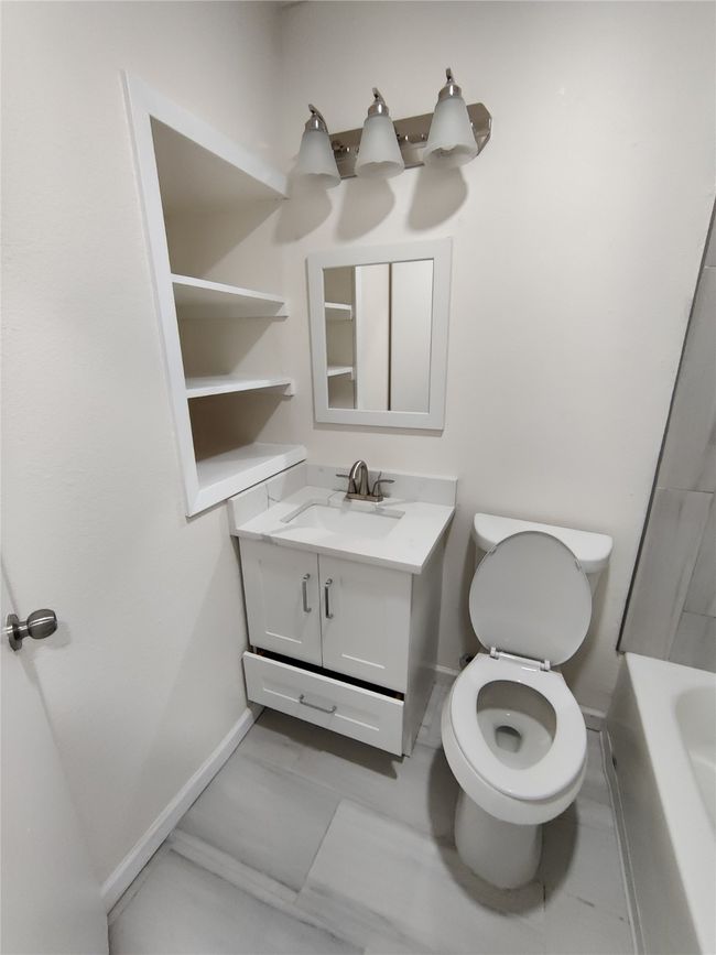 Bathroom with tile patterned flooring, toilet, a washtub, and vanity | Image 8