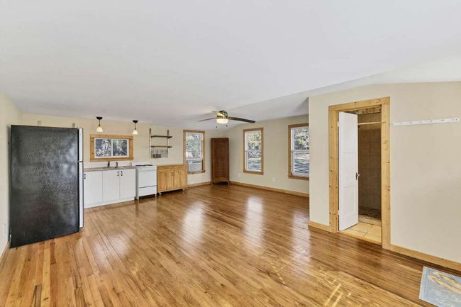Unfurnished living room featuring light wood-style flooring, a sink, ceiling fan, and baseboards | Image 17