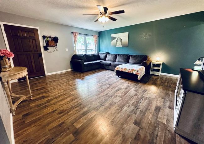 Living room featuring dark wood-type flooring, a ceiling fan, a textured ceiling, and baseboards | Image 8