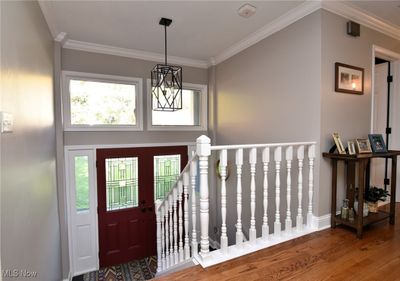 Entrance foyer with wood-type flooring, ornamental molding, and an inviting chandelier | Image 2