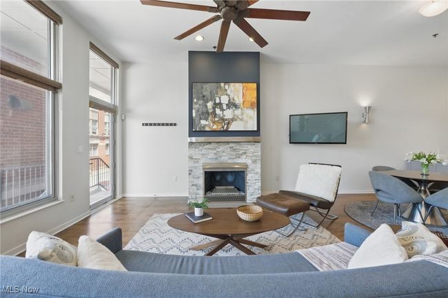 Living room featuring visible vents, baseboards, wood finished floors, ceiling fan, and a stone fireplace | Image 6