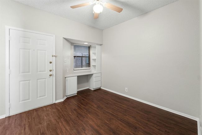 Spare room with ceiling fan, built in study area, baseboards, a textured ceiling, and dark wood-type flooring | Image 10