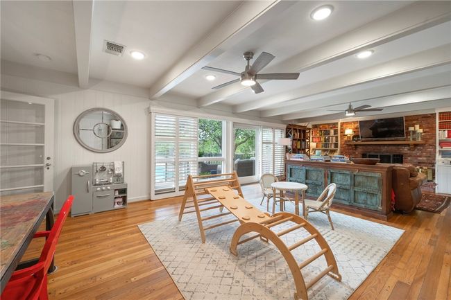 Dining room featuring ceiling fan, light wood-type flooring, beam ceiling, a fireplace, and built in features | Image 16