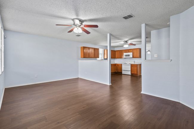 Unfurnished living room with ceiling fan and dark wood-type flooring | Image 10