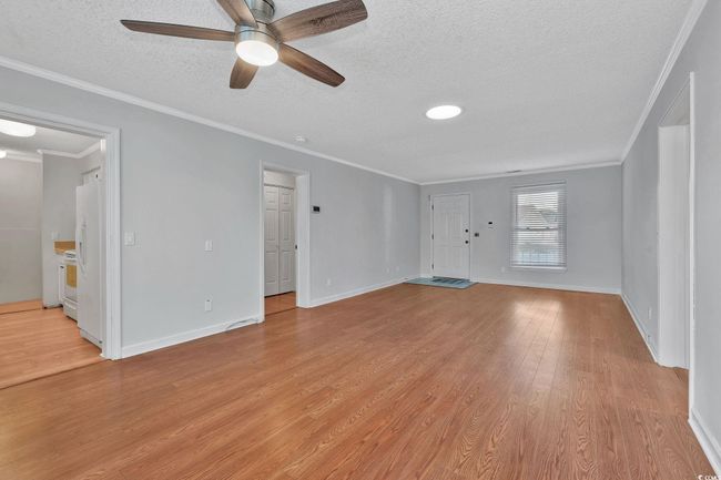 Spare room featuring crown molding, ceiling fan, a textured ceiling, and light wood-type flooring | Image 10