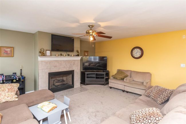 Carpeted living room featuring ceiling fan and a tile fireplace | Image 16