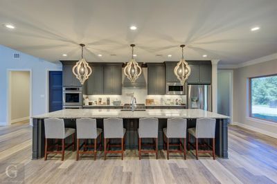 Kitchen with appliances with stainless steel finishes, light hardwood / wood-style floors, decorative light fixtures, and a large island | Image 3