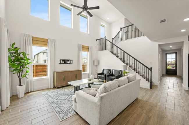 Living area featuring a ceiling fan, light wood-style flooring, stairs, a towering ceiling, and recessed lighting | Image 15