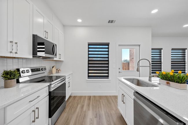 Kitchen with appliances with stainless steel finishes, light wood-style floors, light stone counters, backsplash, and recessed lighting | Image 8