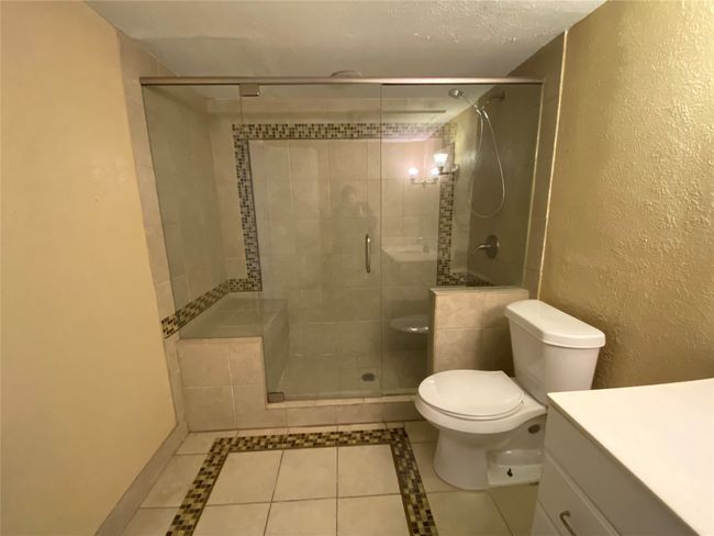 Full bathroom with toilet, tile patterned flooring, a textured wall, and vanity | Image 16