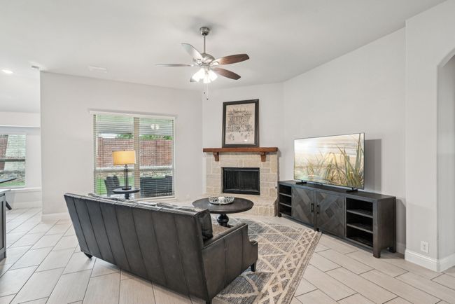 Living room with ceiling fan, a stone fireplace, baseboards, and arched walkways | Image 14