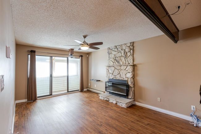 Unfurnished living room featuring baseboards, a textured ceiling, wood finished floors, and a ceiling fan | Image 20