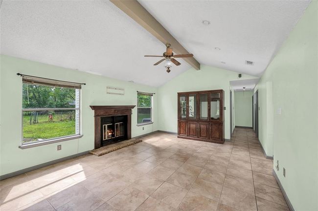 Bright and inviting living room with a cozy fireplace, expansive windows, and elegant tile flooring. | Image 18
