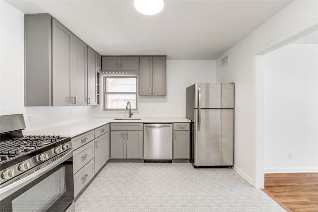 Kitchen featuring appliances with stainless steel finishes, gray cabinets, a sink, light countertops, and baseboards | Image 9