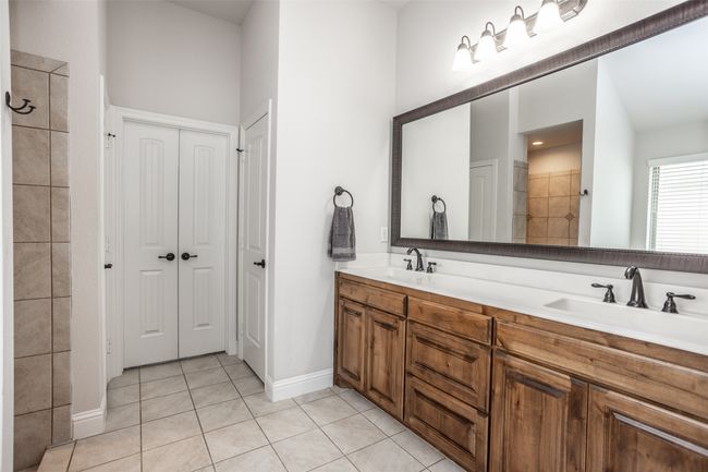 Bathroom featuring double vanity, tile patterned floors, a closet, and tiled shower | Image 25