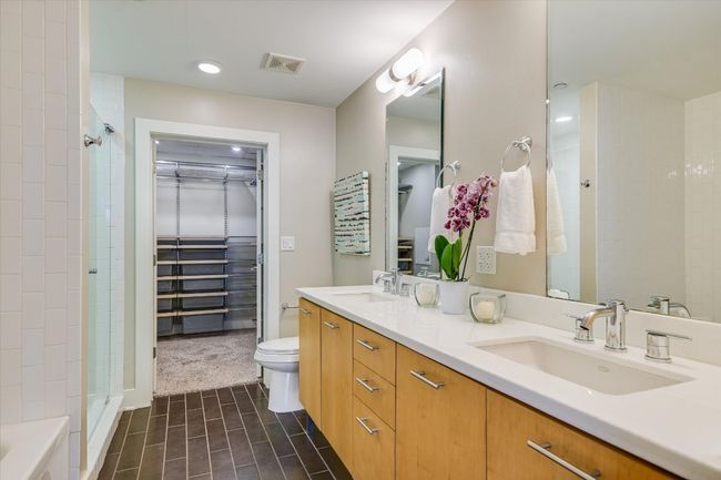 Full bathroom featuring double vanity, a spacious closet, tiled shower, and a sink | Image 10