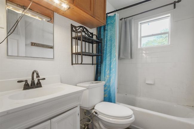 Full bathroom with shower / bath combo, toilet, tile walls, vanity, and decorative backsplash | Image 9