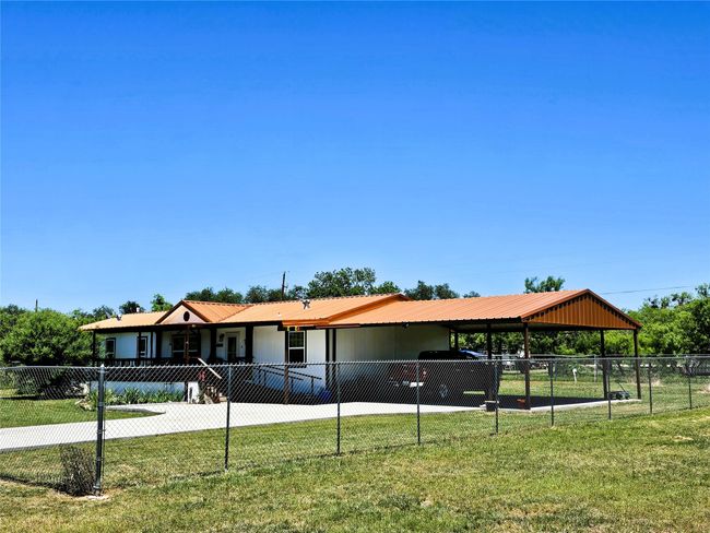 Ranch-style house featuring metal roof, a carport, and driveway | Image 22