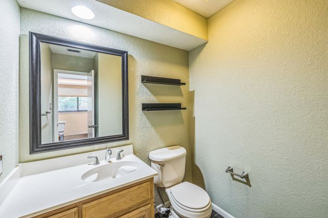 Half bathroom featuring a textured wall, toilet, and vanity | Image 21