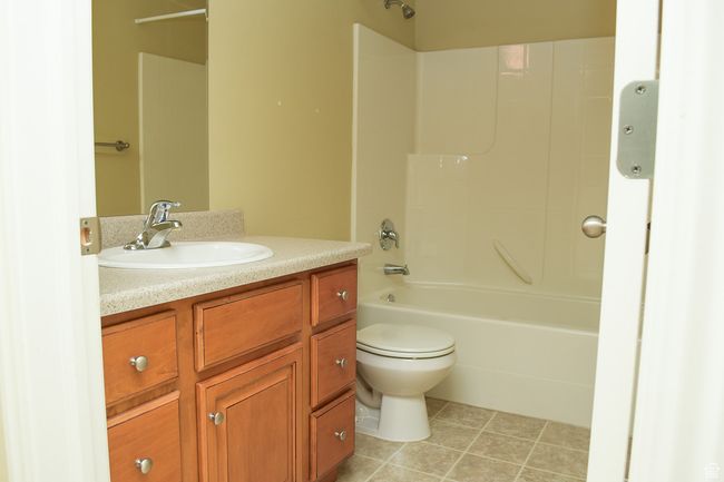 Bathroom featuring tile patterned flooring, vanity, toilet, and shower / washtub combination | Image 9