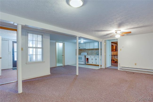 2nd unit living room with a baseboard heating unit, a textured ceiling, ceiling fan, and carpet floors | Image 32