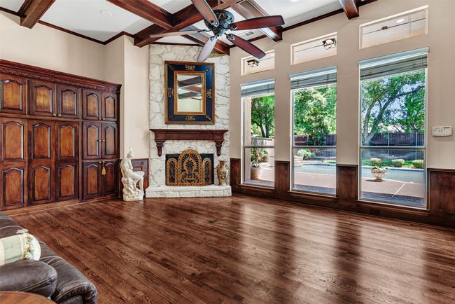 Even the informal family room is gorgeous! Wood floors, beamed ceiling, a wall of built-in cabinets and entertainment center, plus a stone fireplace and breathtaking pool views! | Image 18